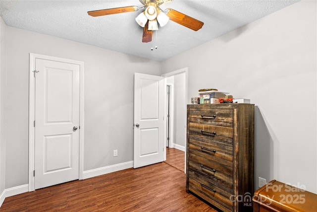 bedroom with ceiling fan, wood-type flooring, and a textured ceiling