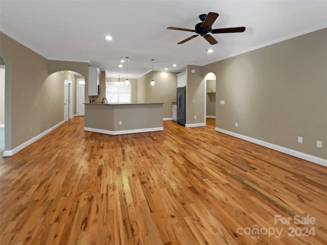 unfurnished living room featuring ornamental molding, light hardwood / wood-style flooring, and ceiling fan with notable chandelier