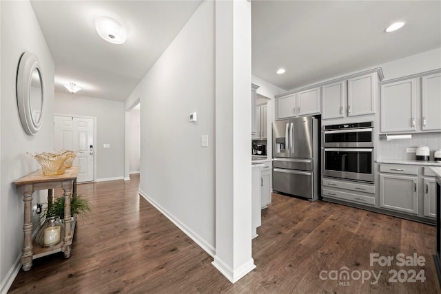 kitchen featuring appliances with stainless steel finishes, gray cabinetry, dark hardwood / wood-style floors, and tasteful backsplash