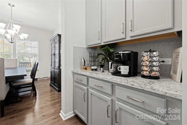 kitchen featuring a chandelier, dark wood-type flooring, pendant lighting, and backsplash