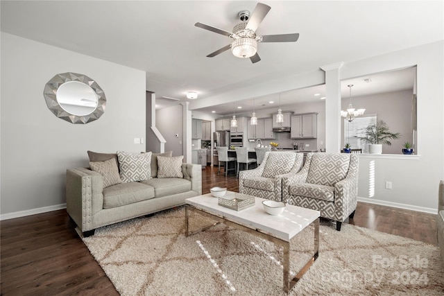 living room with ornate columns, dark hardwood / wood-style flooring, and ceiling fan with notable chandelier