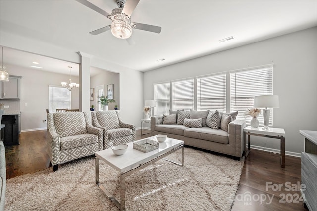 living room featuring dark hardwood / wood-style flooring and ceiling fan with notable chandelier