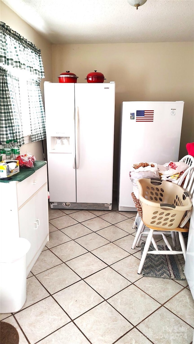 kitchen with a textured ceiling, white refrigerator, and white refrigerator with ice dispenser