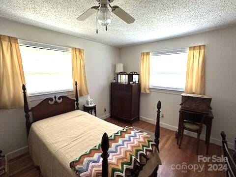 bedroom with a textured ceiling, hardwood / wood-style flooring, and ceiling fan