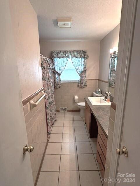 bathroom with vanity, tile patterned floors, tile walls, and toilet