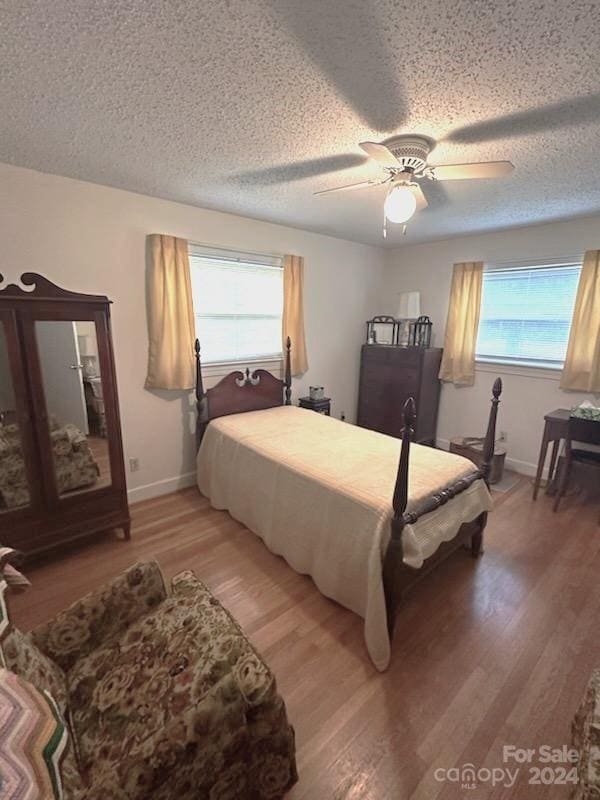 bedroom with wood-type flooring, multiple windows, and ceiling fan