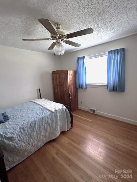 bedroom featuring hardwood / wood-style flooring, a textured ceiling, and ceiling fan