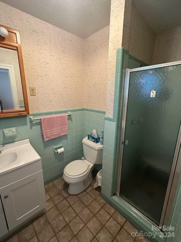 bathroom featuring toilet, vanity, a textured ceiling, and a shower with shower door