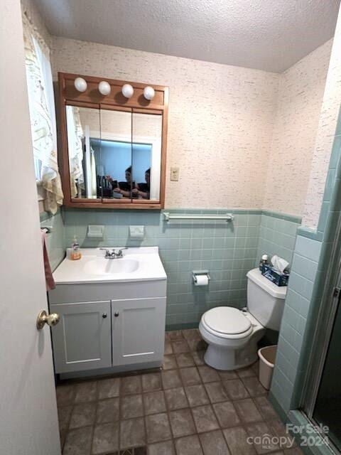 bathroom with tile walls, tile patterned floors, vanity, a textured ceiling, and toilet