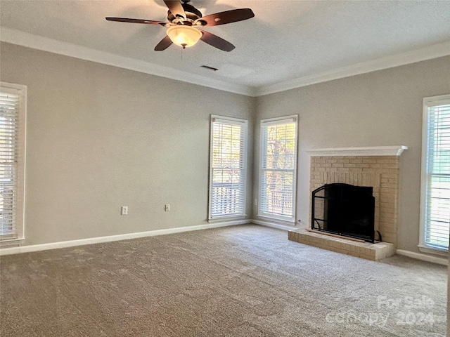 unfurnished living room with carpet, a brick fireplace, a textured ceiling, ceiling fan, and crown molding