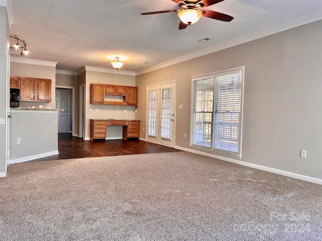 unfurnished living room with a textured ceiling, dark carpet, ceiling fan, and ornamental molding