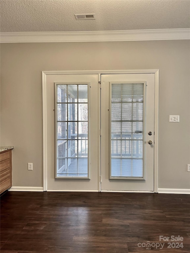 doorway with crown molding, a textured ceiling, and dark wood-type flooring