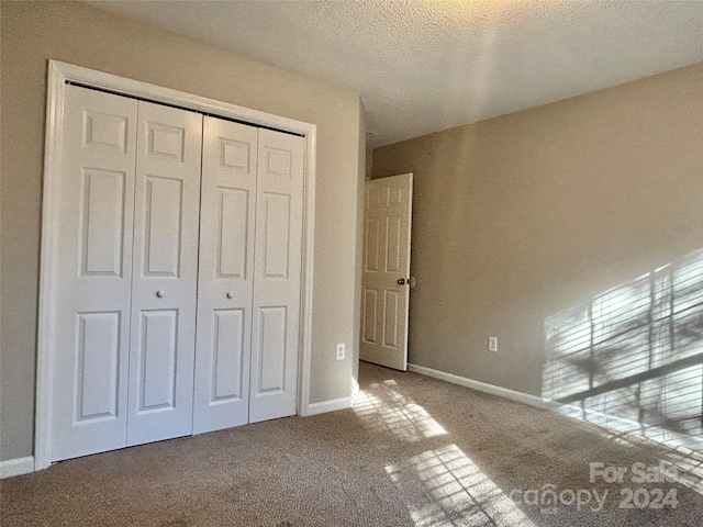 unfurnished bedroom with carpet flooring, a closet, and a textured ceiling