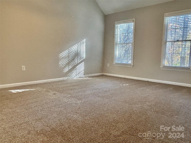 carpeted spare room with vaulted ceiling