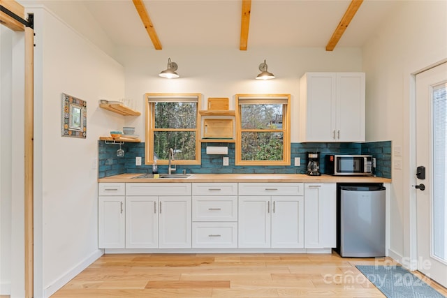 kitchen featuring beam ceiling, tasteful backsplash, white cabinetry, and appliances with stainless steel finishes