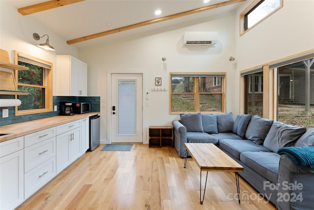 living room featuring an AC wall unit, high vaulted ceiling, beam ceiling, and light wood-type flooring