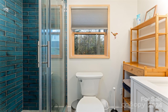 bathroom featuring a shower with door, vanity, and toilet