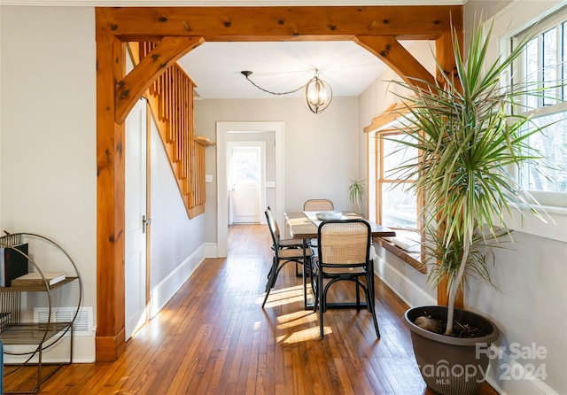 dining space with dark hardwood / wood-style floors, a wealth of natural light, and an inviting chandelier