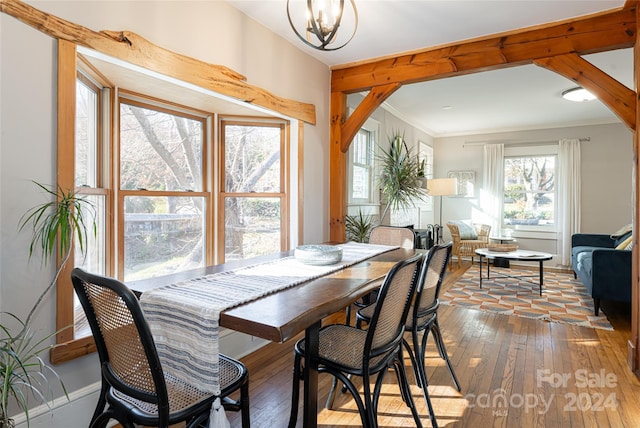 dining space with hardwood / wood-style floors, crown molding, and a notable chandelier