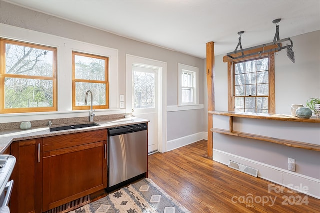 kitchen with pendant lighting, dishwasher, white stove, sink, and hardwood / wood-style flooring