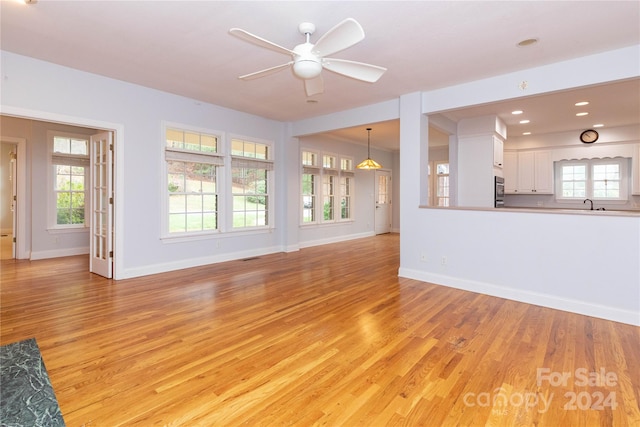 unfurnished living room featuring ceiling fan, light wood-type flooring, and a wealth of natural light