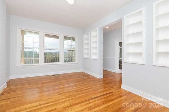 spare room with light hardwood / wood-style floors and built in features