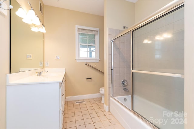 full bathroom with tile patterned floors, vanity, toilet, and bath / shower combo with glass door