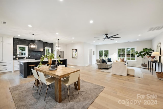 dining space featuring ceiling fan with notable chandelier and light wood-type flooring