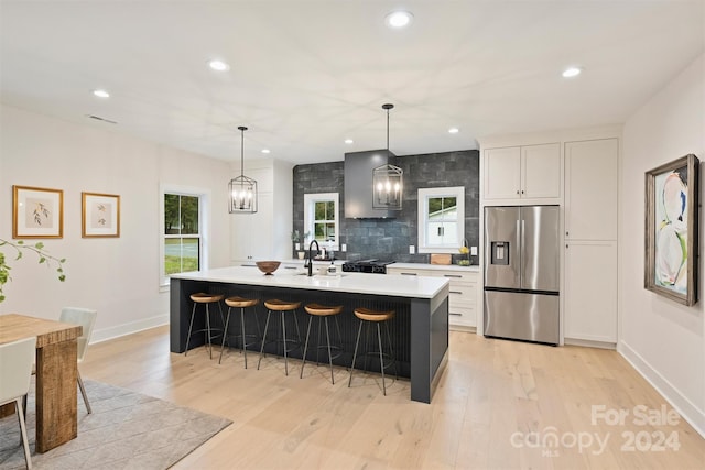 kitchen featuring light hardwood / wood-style floors, an island with sink, white cabinets, and stainless steel fridge with ice dispenser