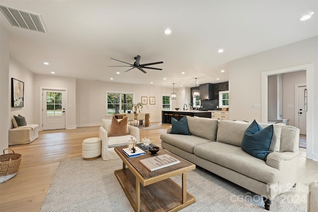 living room featuring light hardwood / wood-style floors, sink, and ceiling fan