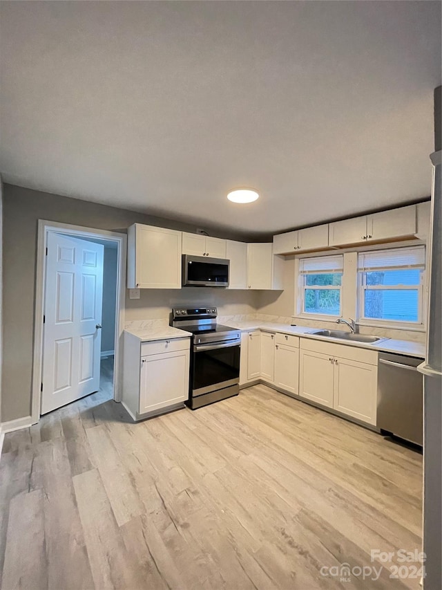 kitchen featuring sink, appliances with stainless steel finishes, light wood-type flooring, and white cabinetry