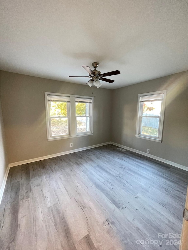 empty room with light hardwood / wood-style floors, plenty of natural light, and ceiling fan