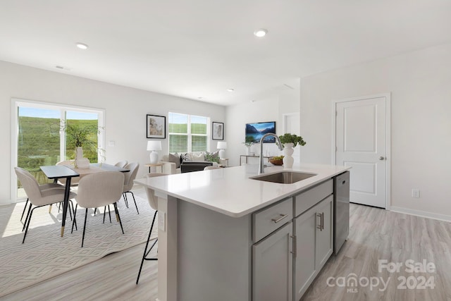 kitchen with gray cabinets, a healthy amount of sunlight, sink, and a center island with sink