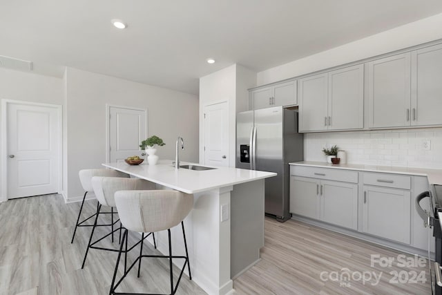 kitchen featuring light hardwood / wood-style flooring, sink, an island with sink, and stainless steel refrigerator with ice dispenser