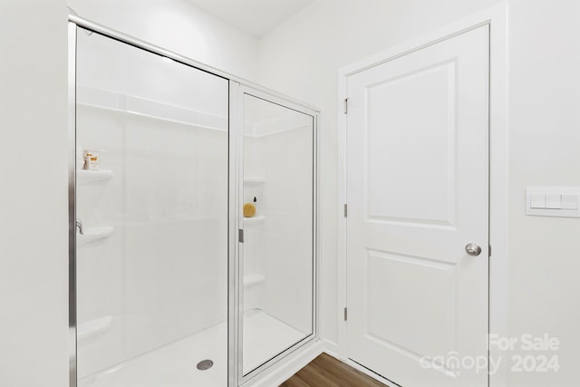 bathroom featuring hardwood / wood-style flooring and a shower with shower door