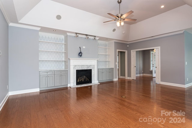 unfurnished living room featuring ceiling fan, a premium fireplace, vaulted ceiling, ornamental molding, and dark wood-type flooring