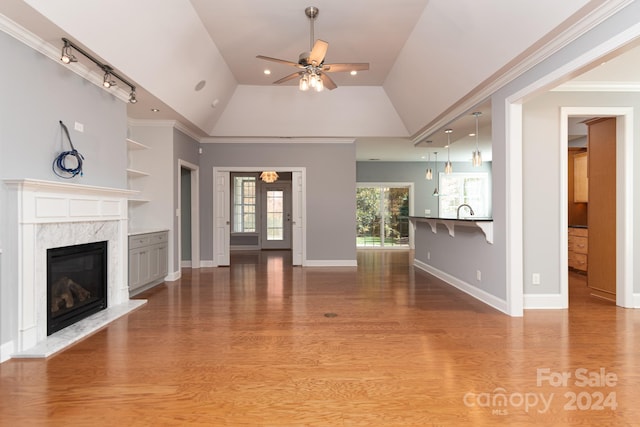 unfurnished living room featuring crown molding, a high end fireplace, wood-type flooring, and vaulted ceiling