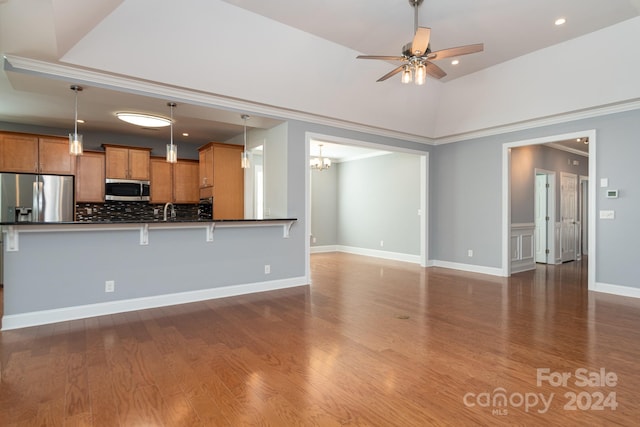 kitchen with kitchen peninsula, stainless steel appliances, pendant lighting, and a breakfast bar area