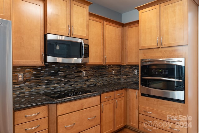 kitchen featuring appliances with stainless steel finishes, tasteful backsplash, and dark stone countertops