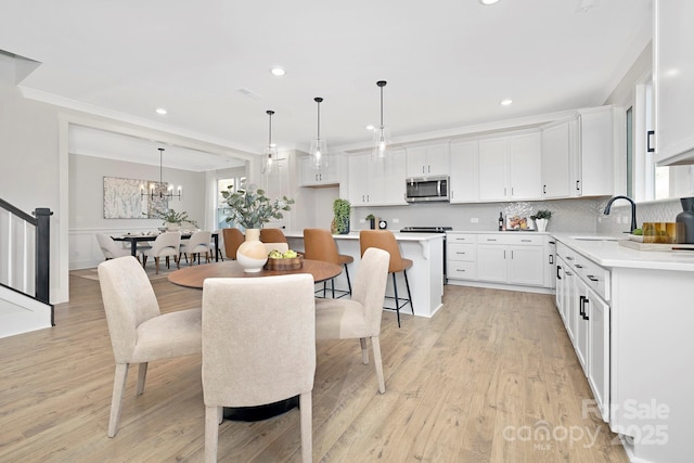 kitchen featuring sink, decorative light fixtures, a kitchen island, light hardwood / wood-style floors, and white cabinets