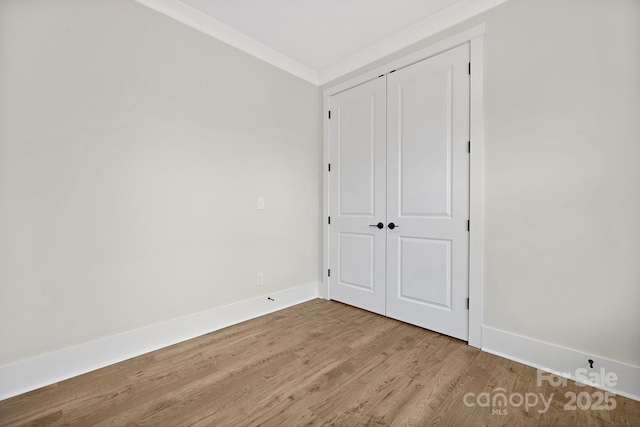 unfurnished bedroom with crown molding, wood-type flooring, and a closet