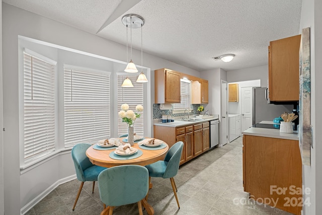 kitchen featuring decorative backsplash, hanging light fixtures, a textured ceiling, sink, and appliances with stainless steel finishes