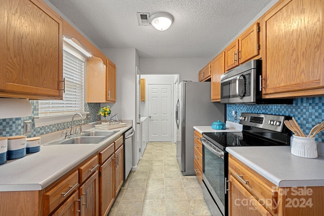 kitchen featuring stainless steel appliances, a textured ceiling, sink, and decorative backsplash