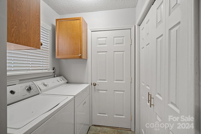 laundry area with cabinets, washing machine and clothes dryer, and a textured ceiling