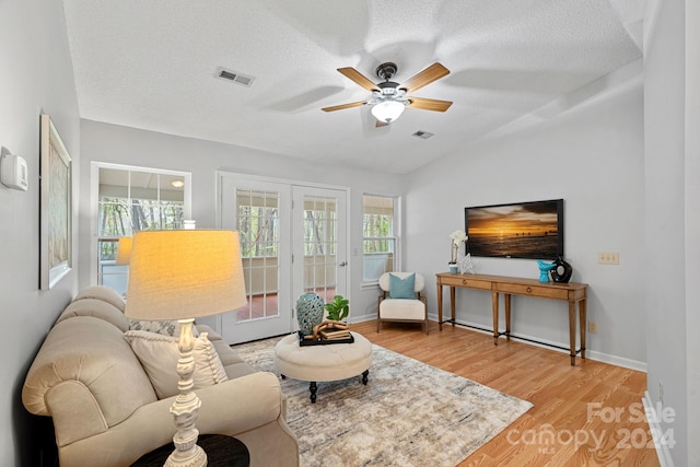 living room with french doors, light hardwood / wood-style floors, and a textured ceiling