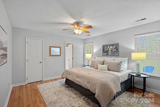 bedroom featuring ceiling fan, a textured ceiling, and light wood-type flooring