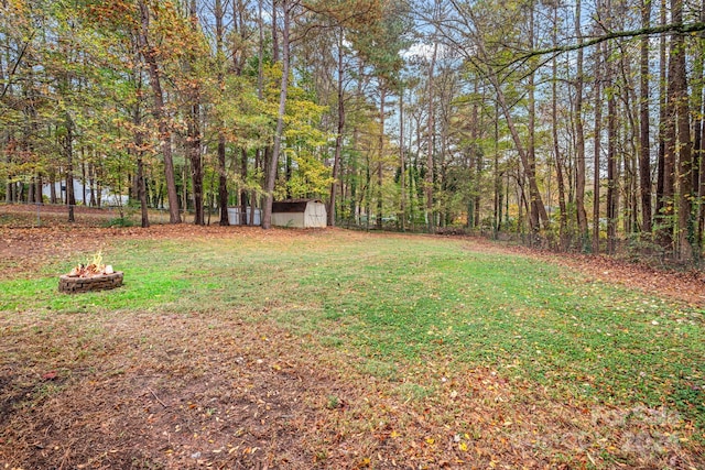 view of yard featuring a storage shed and an outdoor fire pit