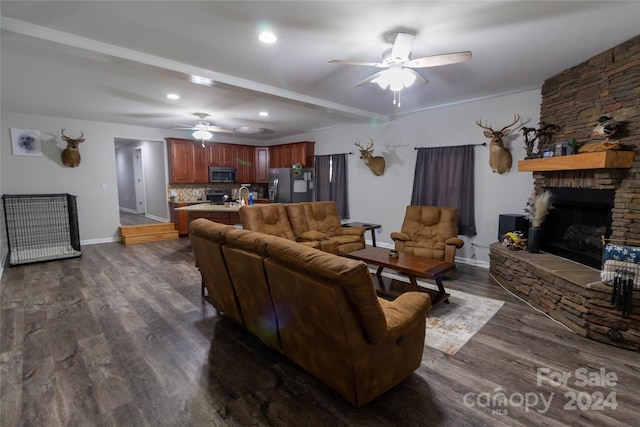 living room featuring a stone fireplace, ceiling fan, sink, and dark hardwood / wood-style floors