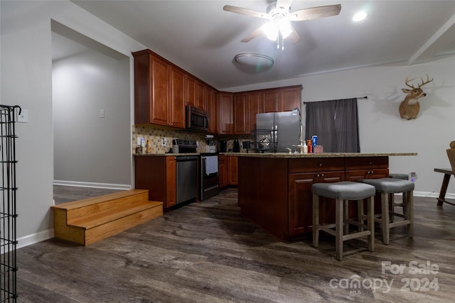 kitchen with dark wood-type flooring, appliances with stainless steel finishes, and a center island