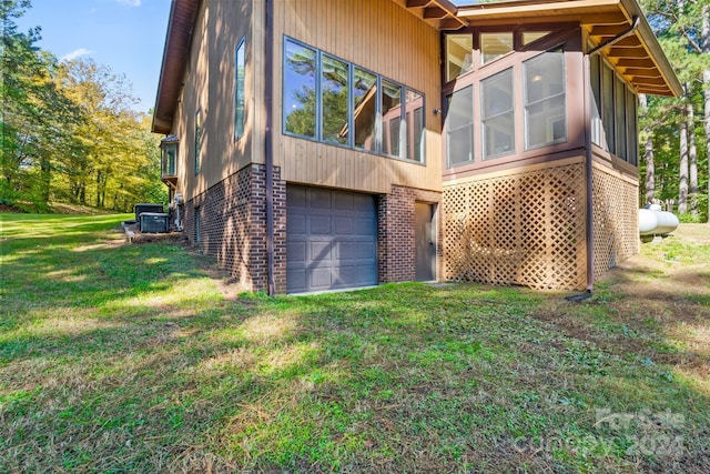 view of side of property featuring a sunroom, a garage, and a lawn